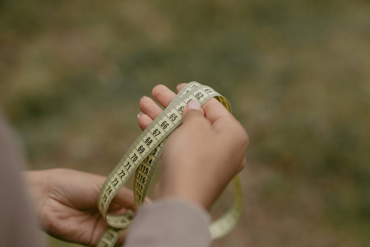 services-04 Hands holding a rolled measuring tape, focused on numbers and markings.