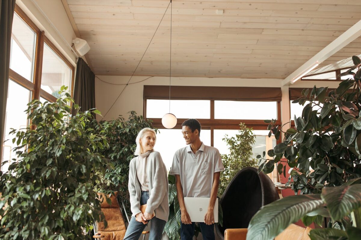 Diverse colleagues smiling in a plant-filled creative office setting.